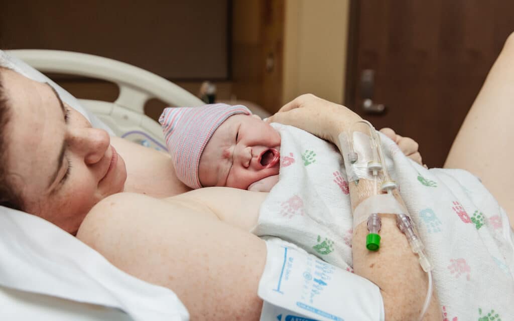 Mother holding her newborn skin-to-skin after a hospital birth.