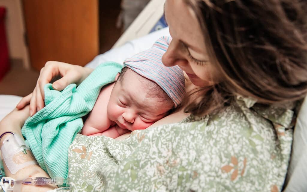 Mother looking down at her newborn baby after birth, sharing a quiet bonding moment.